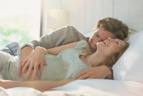 Embarazada con su pareja en la cama